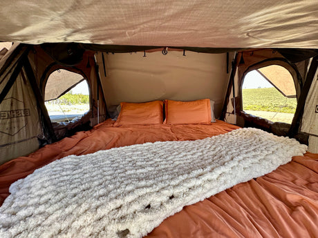 Cozy rooftop tent bed inside an RV rental, ready for adventure. Enjoy comfy camping with stunning views!