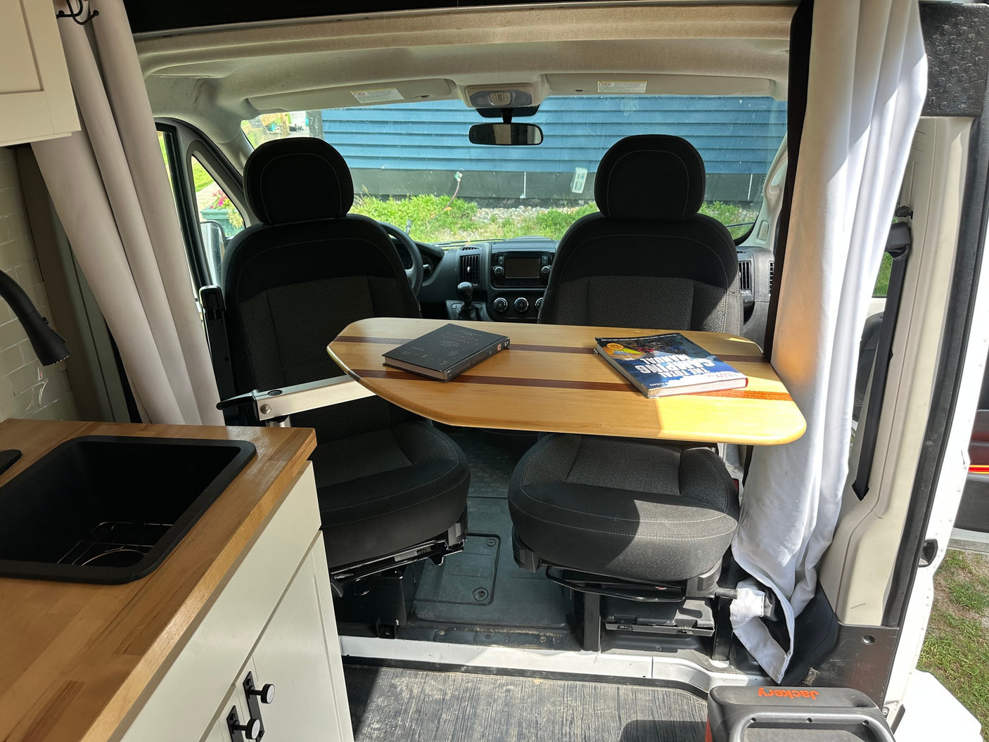 and overhead storage cabinets for comfortable travel.|RV rental interior with swivel seats and a unique wooden table