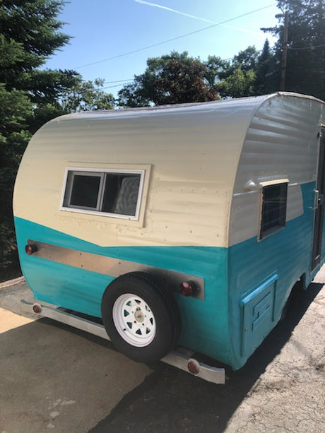 Explore with this charming vintage RV rental! Teal & cream camper with rear spare tire, ready for adventure.
