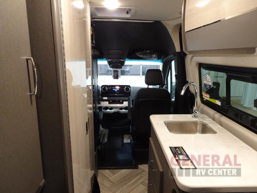 Inside a modern RV rental: a compact galley kitchen with sink and faucet, extending to the front cockpit. — photo 4
