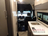 Inside a modern RV rental: a compact galley kitchen with sink and faucet, extending to the front cockpit.