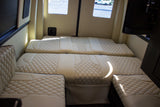 Cream quilted seating converts to beds inside this spacious RV rental, offering comfort and style.
