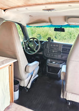 Step inside this RV rental conversion van! Front cabin view showing the dashboard, steering wheel, seats, and custom wooden ceiling.