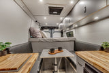 Explore this stylish rv rental interior featuring a comfy bed, dining nook with mugs, wood accents, and ample storage.