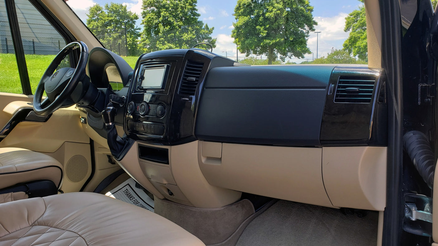 Luxury RV rental interior featuring a modern dashboard, steering wheel, and plush tan leather seating for comfortable travel.