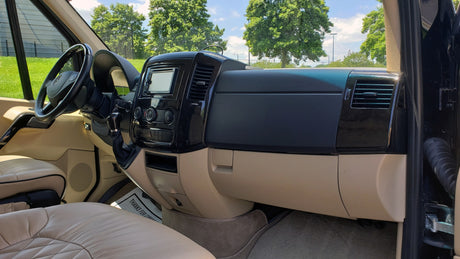 Luxury RV rental interior featuring a modern dashboard, steering wheel, and plush tan leather seating for comfortable travel.