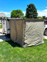 An RV rental with an attached tent setup on grass and pavement under a blue sky, ready for camping and outdoor adventure.