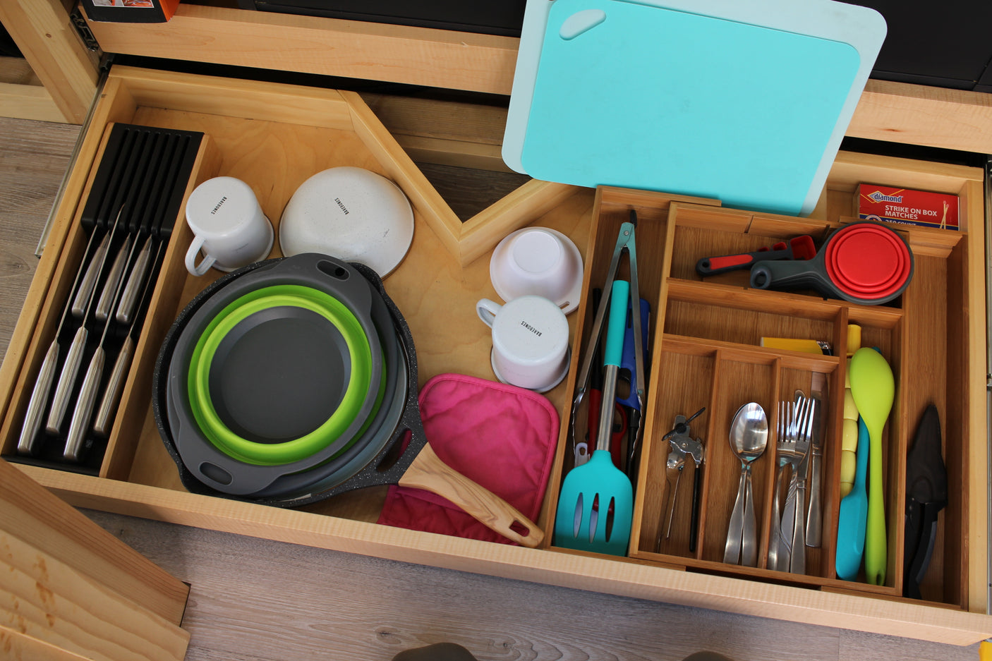Organized kitchen essentials in an RV rental drawer, featuring knives, cookware, and utensils for compact living.