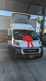 White Ram camper van, a common RV rental choice, sports a festive red bow.