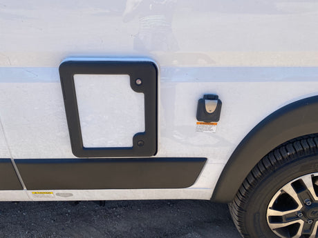 Close-up of an RV rental's side: electrical hookup, utility panel, tire. Warning labels for power and gray waste tank.