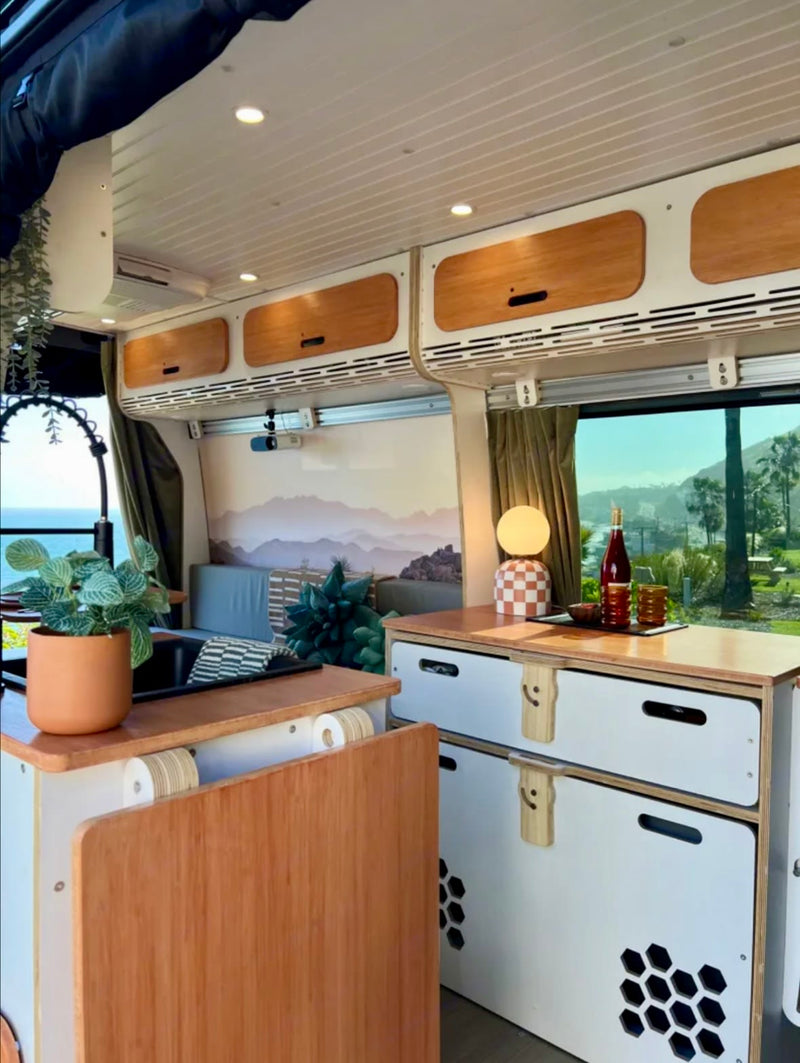  and a counter. Enjoy stunning ocean views from this cozy camper van.|Scenic RV rental dining area overlooking the ocean with a palm tree — photo 6