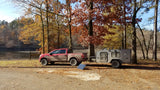 Off-road RV rental: Nissan Titan PRO4X towing an Escapade camper with solar, by a lake with fall foliage.