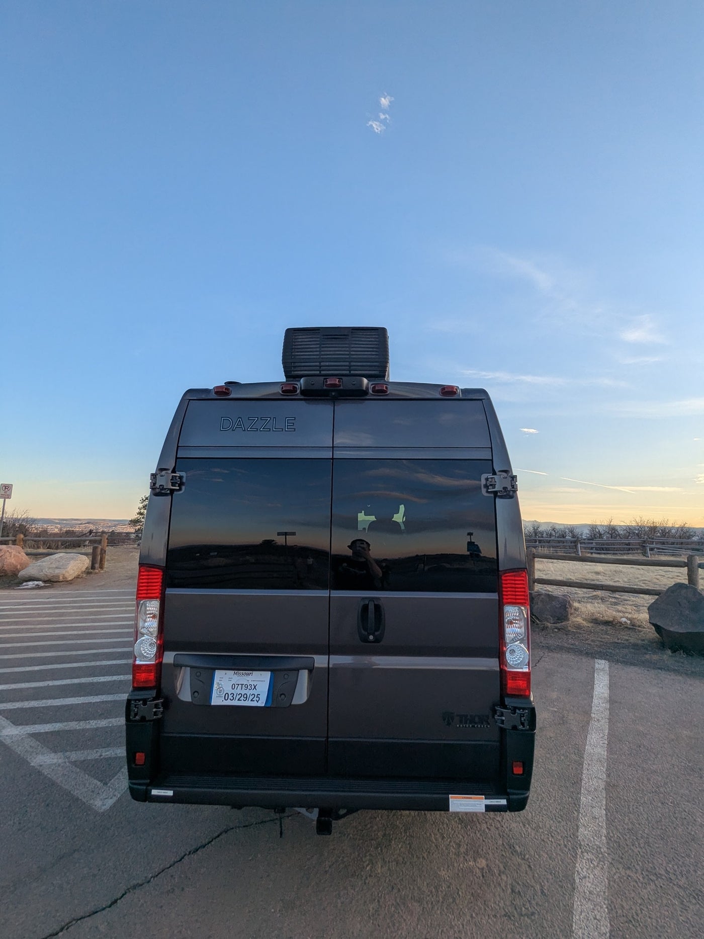 Rear of a dark Dazzle RV rental van, MO plate 07T93X. Parked facing a scenic vista at dusk, ready for adventure. — photo 16