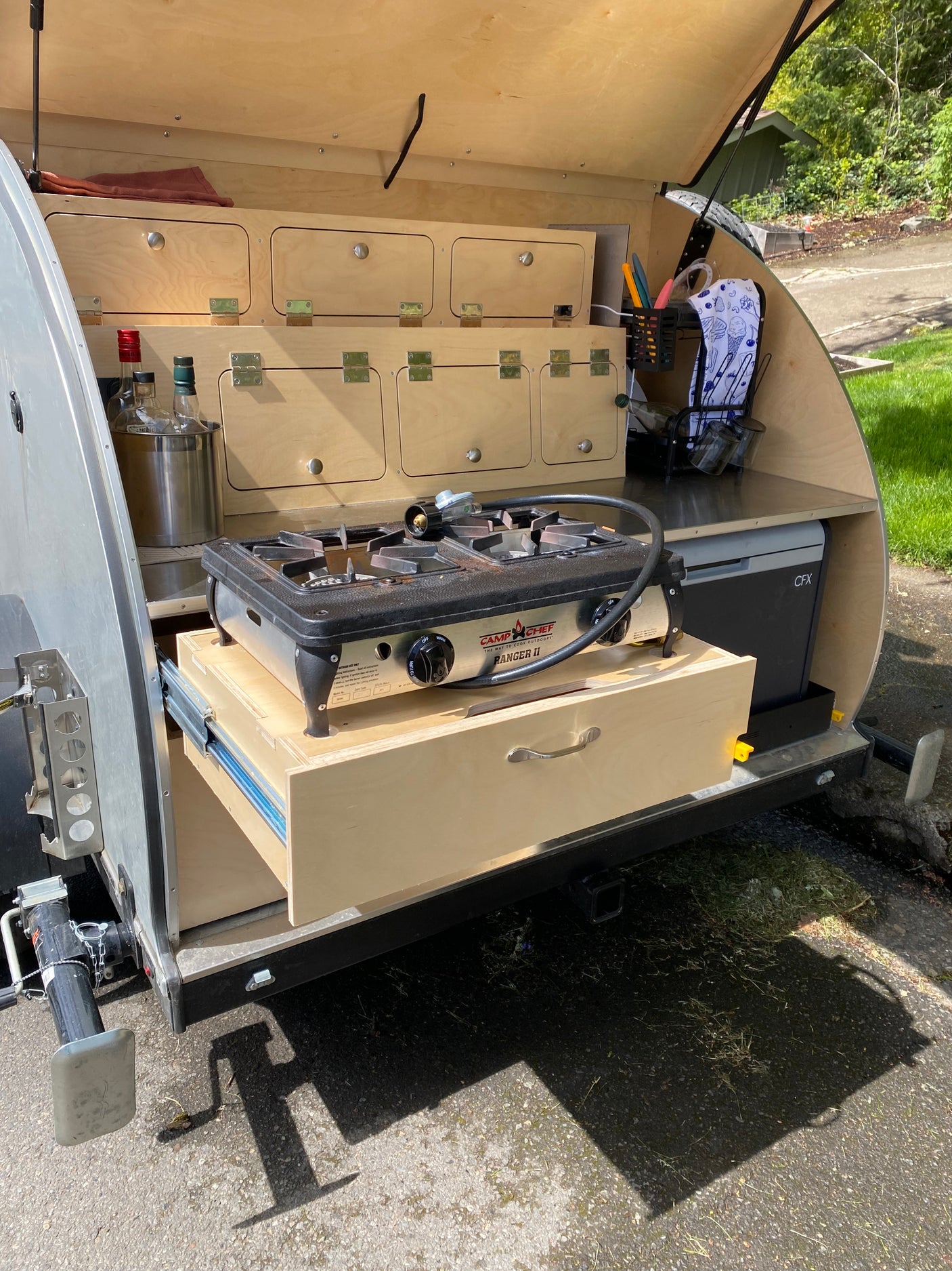 Teardrop RV rental galley with pull-out Camp Chef stove, fridge, and storage, ideal for outdoor cooking.
