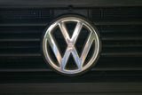 A shiny chrome Volkswagen emblem is centered on a dark vehicle grille. Ready for your next RV rental journey!