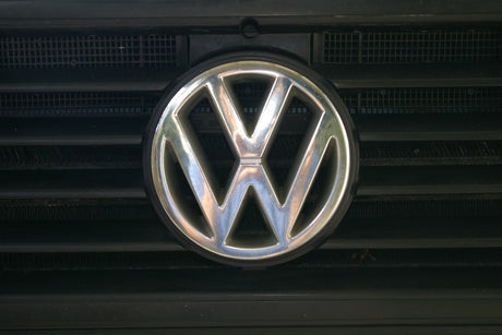 A shiny chrome Volkswagen emblem is centered on a dark vehicle grille. Ready for your next RV rental journey!