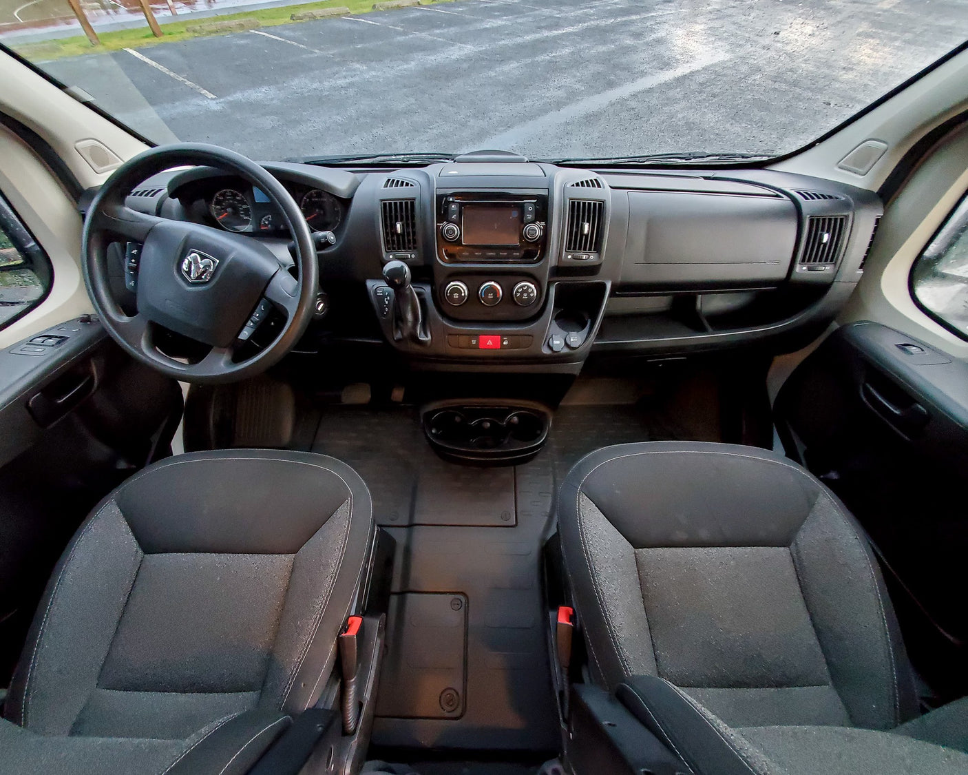 Ram van RV rental interior: overhead view of front cabin with steering wheel, infotainment dashboard, and seats.
