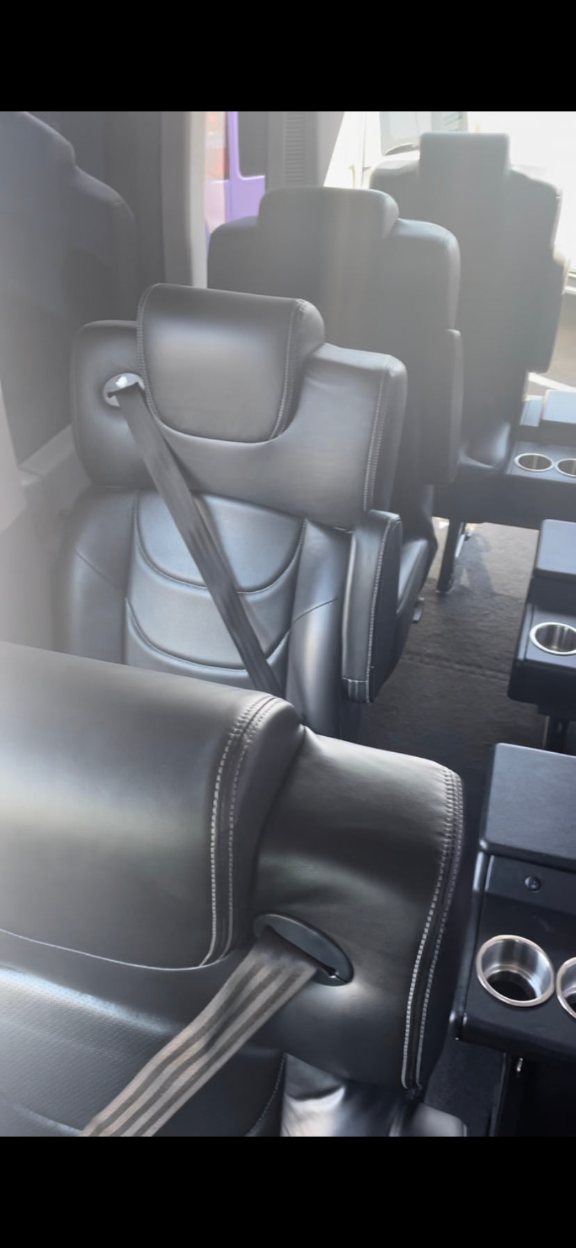 Plush black leather seats with seatbelts and built-in cup holders inside an RV rental, offering comfortable travel.