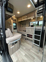 RV rental interior: comfy lounge, integrated kitchenette, and bunk ladder for a cozy, adventure-ready travel experience.