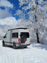 RV rental parked in a snowy landscape with frosted trees and blue sky. Ideal for winter adventure travel.
