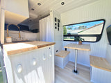 Bright & functional RV rental interior with kitchen, bed, and dining nook, ideal for compact living and travel.