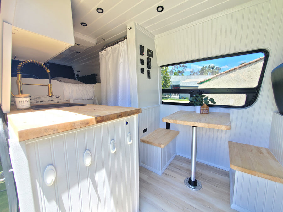 Bright & functional RV rental interior with kitchen, bed, and dining nook, ideal for compact living and travel.