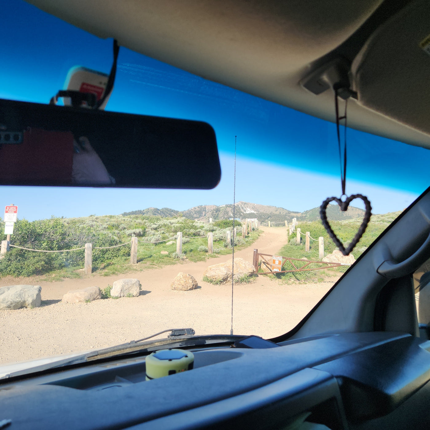Inside an RV rental, looking out at a winding mountain road. A heart charm hangs, inviting scenic travel & adventure. — photo 8
