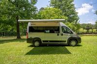 Parked on lush green grass, this gray RV rental offers an extended awning for comfortable outdoor adventures. — photo 8