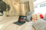 Cozy RV rental interior with laptop, Hello Kitty plushies, & comfy bed. Perfect for a relaxing getaway!