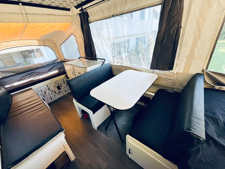 Experience a pop-up camper RV rental with a functional dinette, kitchen, and bed areas. Bright, clean interior.