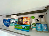 Kirkland paper, Swiffer, Mrs. Meyer's cleaning supplies, and chocolates neatly stored in this RV rental cabinet.