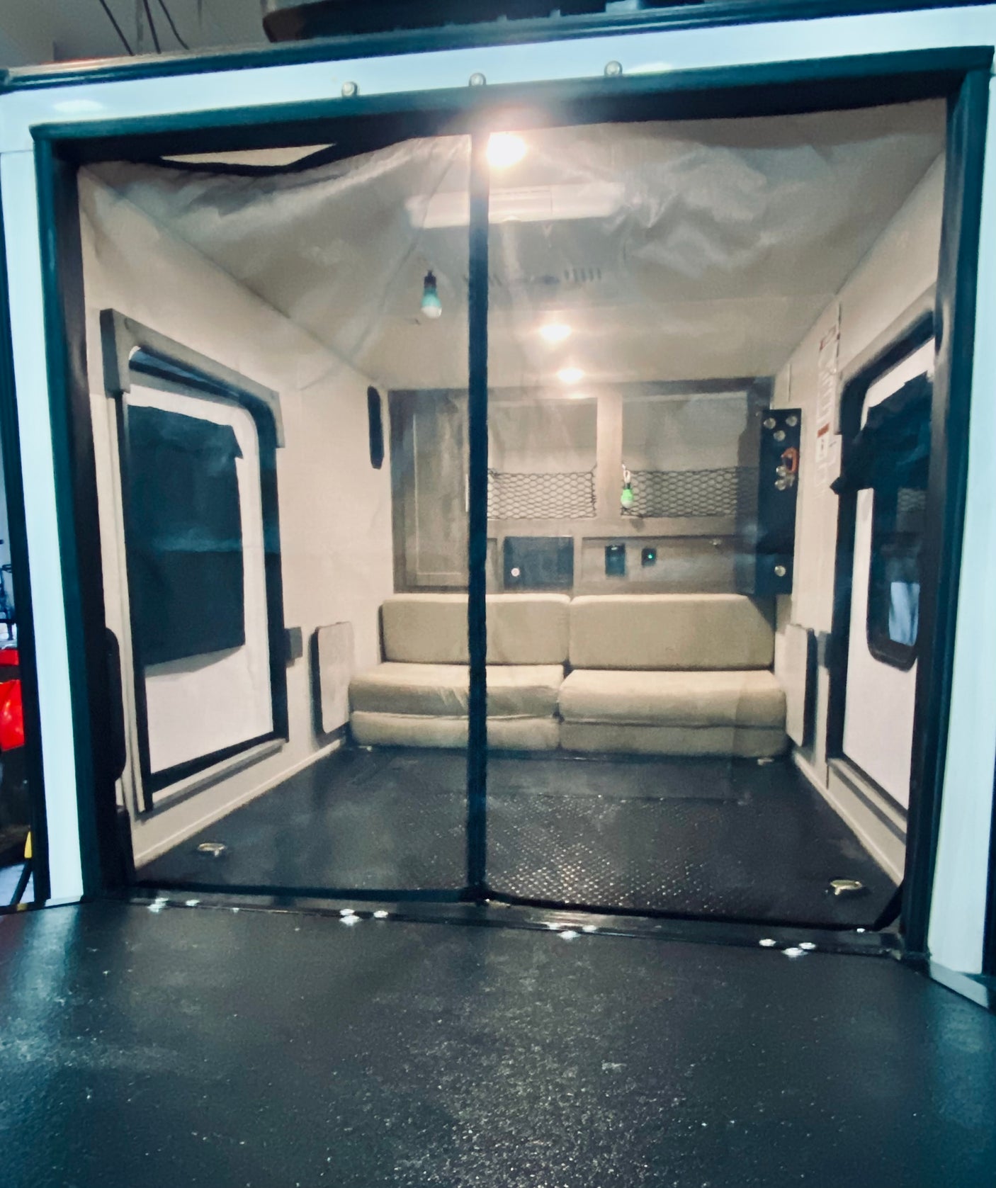 Inside an RV rental toy hauler: A versatile living area with light sofas, rugged floor, and a protective mesh screen at the entrance.