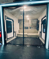 Inside an RV rental toy hauler: A versatile living area with light sofas, rugged floor, and a protective mesh screen at the entrance.