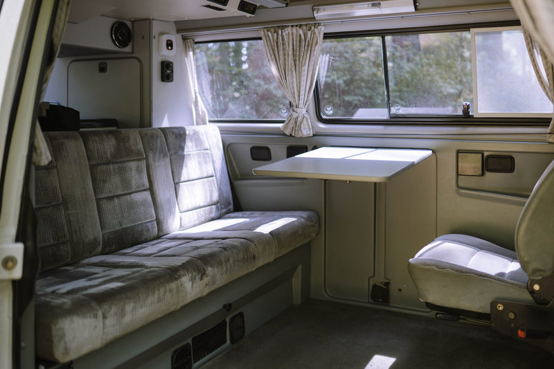  parked in a sunny forest with its side door open.|Interior of a classic RV rental van: driver's view of the dashboard — photo 8
