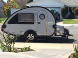 Considering an RV rental? This compact teardrop camper, parked outside a home, is ready for adventure.