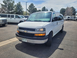 White Chevrolet van parked in an RV rental lot with travel trailers and other vans, ideal for your next trip.