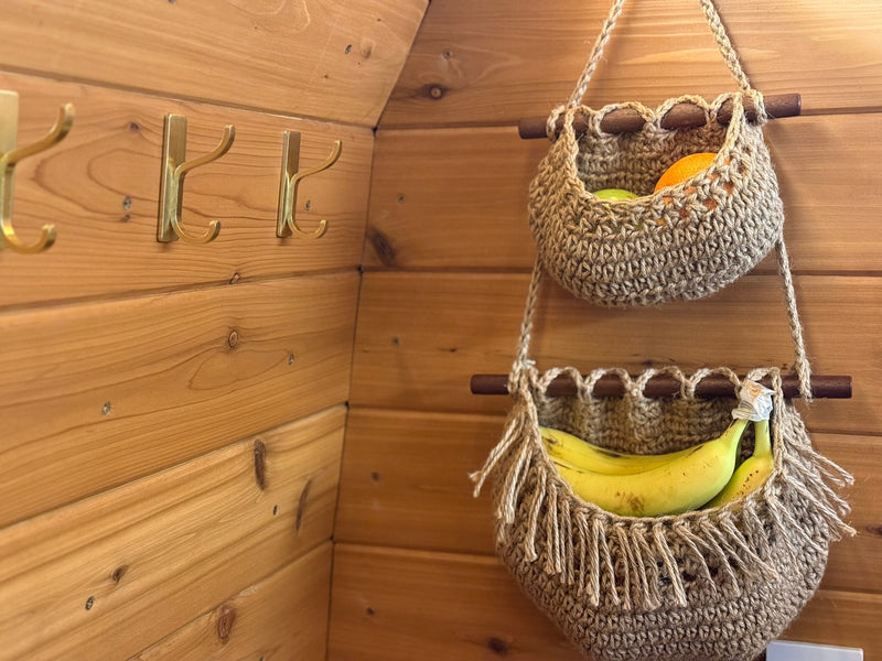 Cozy rv rental interior: wooden walls, brass hooks, and two crocheted baskets holding fruit. Organized storage for your travels. — photo 10