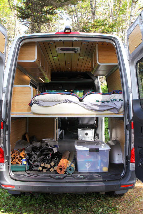 Explore this RV rental's clever interior: a comfortable raised bed, ample under-bed storage, and tasteful wood finishes.