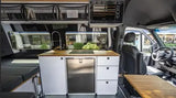 Inside a premium rv rental: compact kitchen with sink, stove, fridge, and comfortable living area with storage.