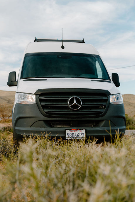 Front view of a white Mercedes Sprinter van, common as an RV rental, parked in an outdoor setting. CA plate 58066P3.