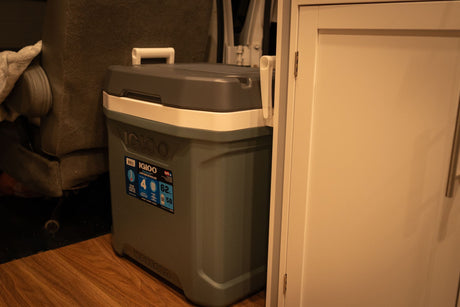 A portable Igloo MaxCold cooler on the floor of an RV rental, essential for travel and cold storage on the go.