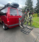 Explore with this red camper van! Featuring roof storage, bike rack, and cargo carrier, it's ready for your RV rental adventure.