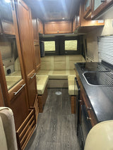 Cozy RV rental interior with kitchen, seating, and wooden cabinetry, perfect for road trips and camping adventures.