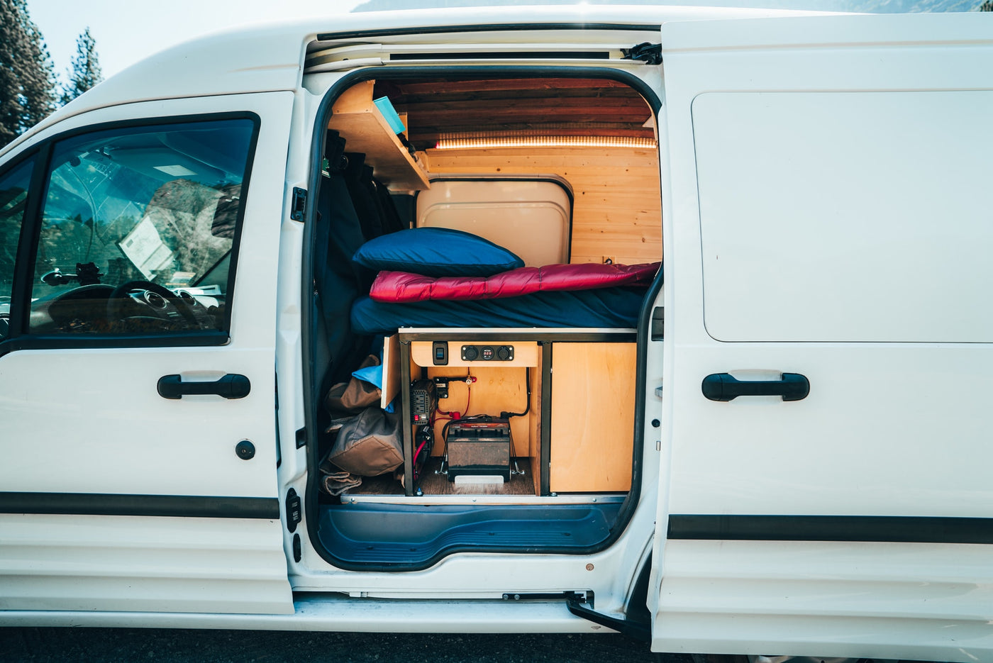  and a robust power setup for mobile living.|A smartphone charges in a custom wooden RV rental interior — photo 5