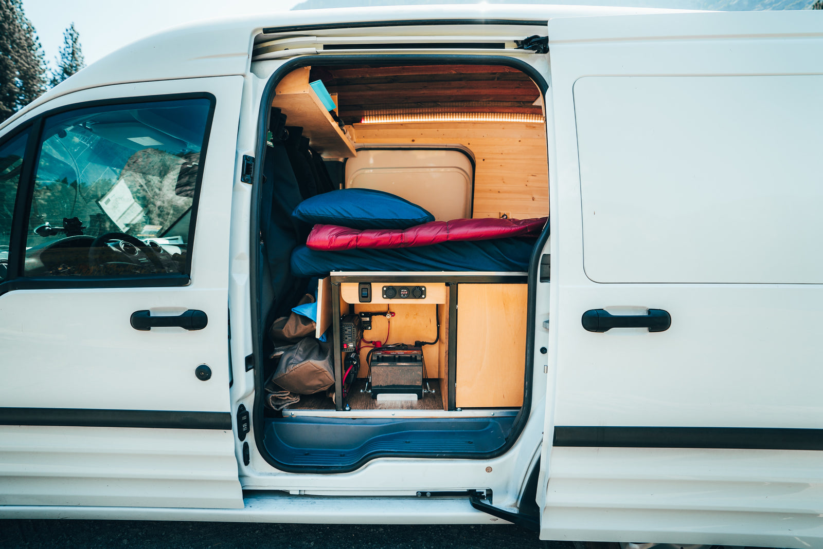 RV rental: Inside a converted camper van, showing the bed, storage, and a robust power setup for mobile living.