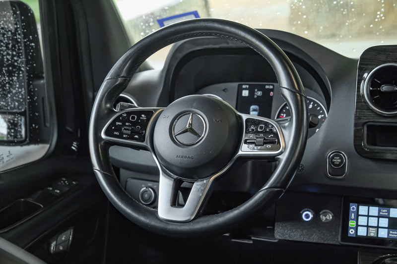 Inside a modern Mercedes-Benz RV rental: a detailed view of the steering wheel and dashboard controls, ready for adventure. — photo 19
