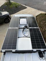 Solar-powered RV rental rooftop with 4 panels, central unit, & wiring for off-grid adventures. View from above.