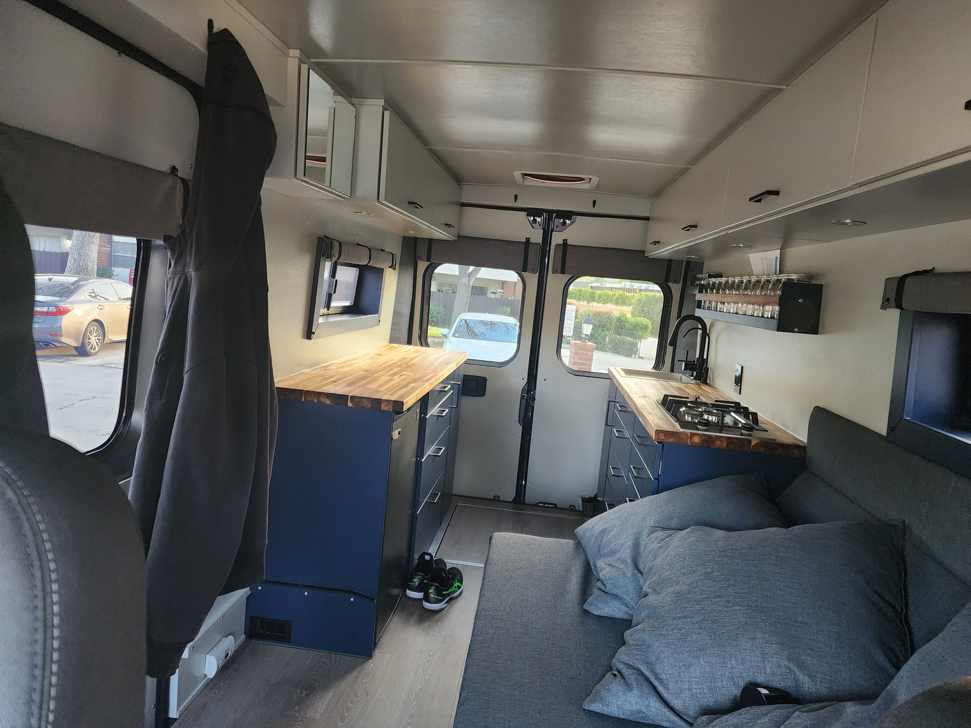 Inside a modern **rv rental**: a compact kitchen with wood counters, comfortable sofa bed, and ample storage for van life.
