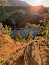 Golden hour illuminates a vast river valley, dense forests, and mountains. Perfect for an RV rental adventure!