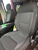 Inside an RV rental: Comfortable black & gray front seats with armrests, white stitching, and visible airbag tags.